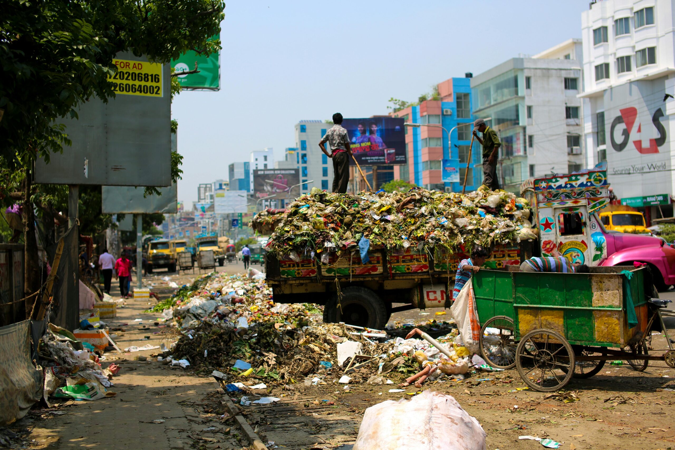 Trash-filled streets with vibrant urban buildings in Bangladesh.