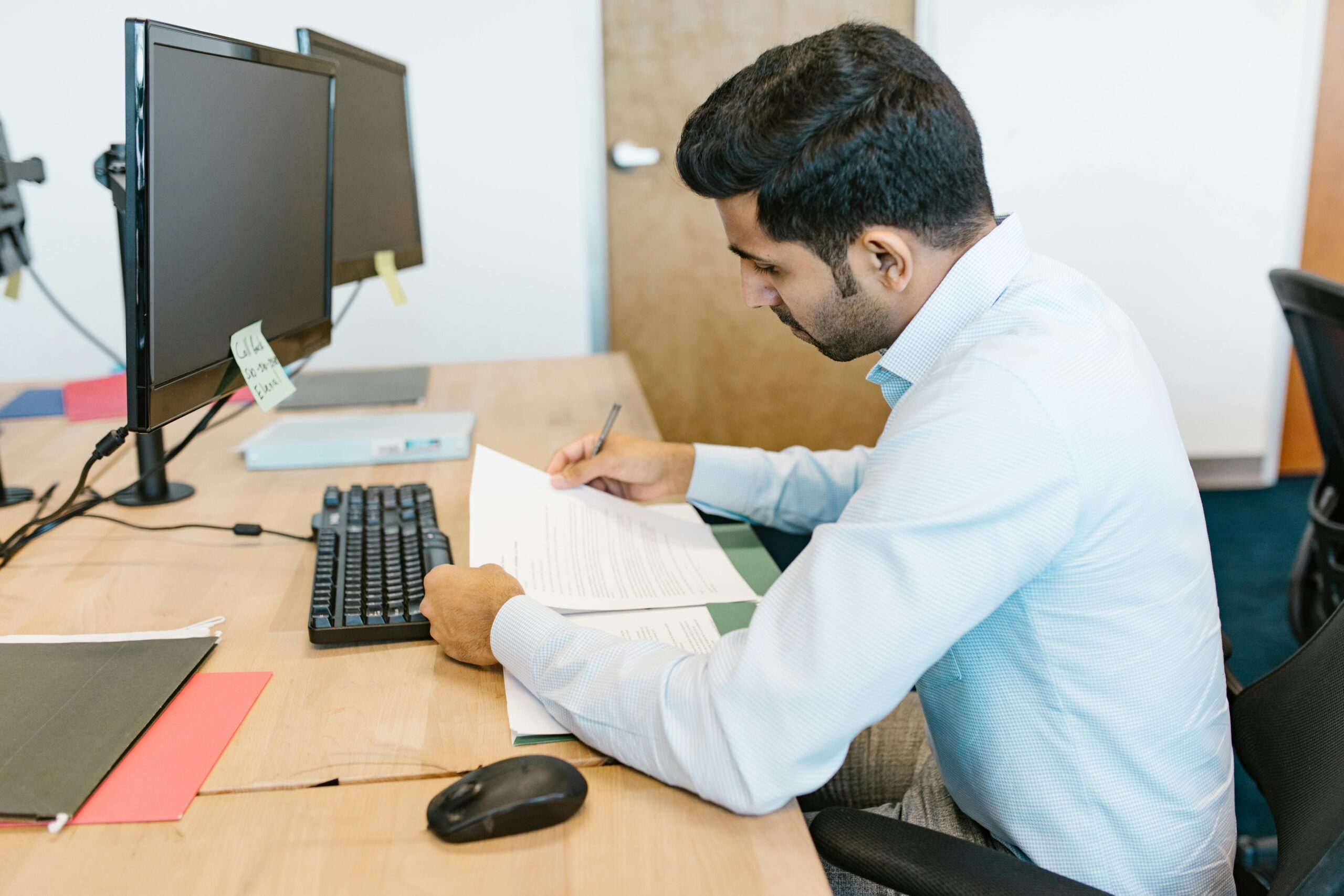 Professional man reviewing documents at his desk in a modern office setting.